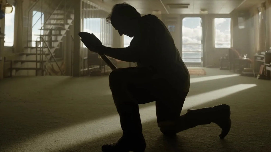 Tom Cruise kneeling with a shovel in a sunlit room in Digger (2026).